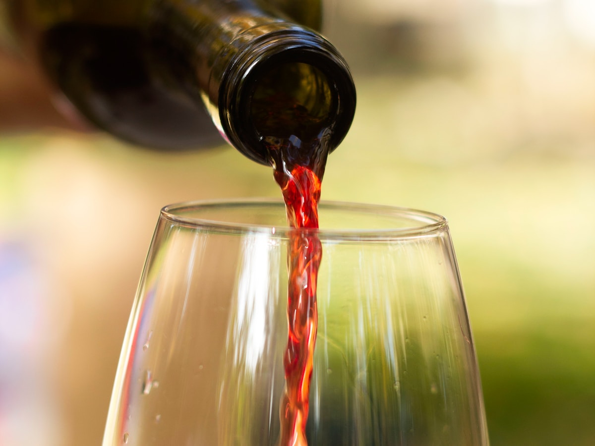 Rotwein wird in ein Glas eingeschenkt